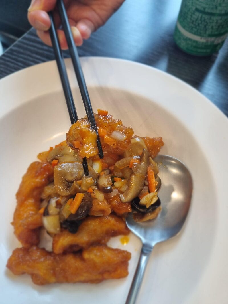 각종 채소와 함께 볶아낸 윤기 흐르는 깐풍기의  젓가락으로 집어 올린 깐풍기